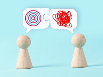 wooden figures with speech bubbles, one with a spiral and one with a messy scribble